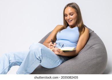 Girl Sitting And Reading A Book On Beanbag Sofa Isolated On White Background