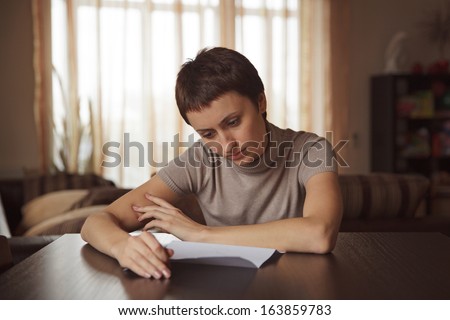 Girl sitting at the table reading a letter