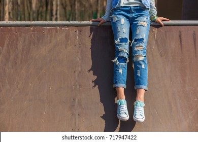 girl is sitting, wearing ripped jeans, hipster style, casual, clothes for youth, no face, lower part of body, sporty style. 