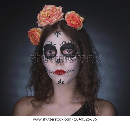 Girl with skeleton makeup and flowers in her hair on a dark background