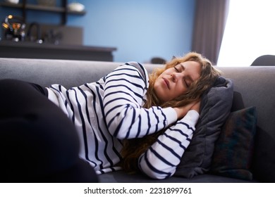 Girl sleeps on cozy sofa in living room at siesta time. Sleeping woman taking nap on the sofa during the day.