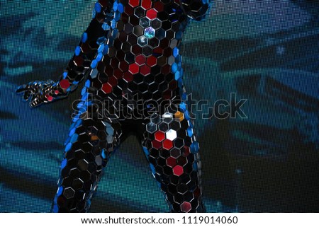 Girl with a slender figure in a fantastic mirror suit with a mask of mirrors performing in the arena
