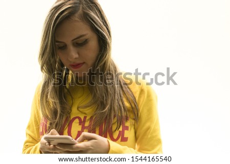 Girl with smartphone and yellow sweater on white background