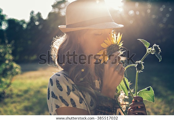 Girl smells sunflower in\
nature