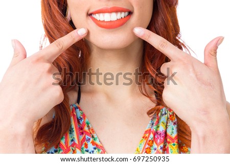 Girl smiles and points with her fingers to her lip. Extreme close up. Redhead woman is wearing a colorful summer dress. 