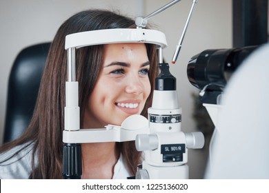 Girl smiling during the process. Optometrist checking vision of young beautiful woman.