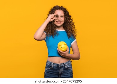 Girl smiling and holding a Bitcoin and piggy bank, showing the connection between digital currency and savings. Exploring cryptocurrency as part of financial literacy course for children  - Powered by Shutterstock