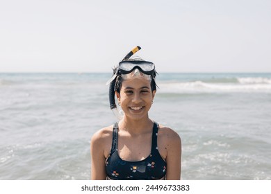 Una niña sonríe y lleva una máscara de snorkel mientras está de pie en el mar Mediterráneo, concepto de diversión y aventura, ya que la niña está lista para Explore el mundo submarino