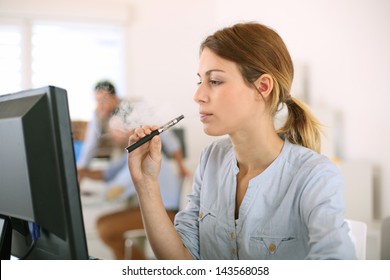 Girl smoking with electronic cigarette in office