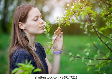 Girl sniffing and enjoying blossoming tree in the spring - Shutterstock ID 659147212