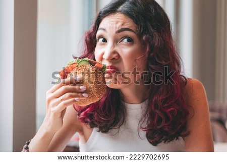 A girl sniffs a spoiled burger. Fast food diet and food poisoning concept