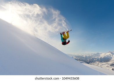 Girl Snowboarder Jumping Front Flip Leaving Behind A Wave Of Snow