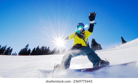 Girl snowboarding on slopes. Sun rays and flare visible.