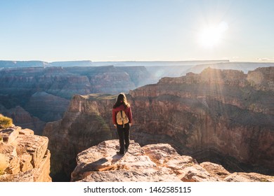 Girl solo traveler on the edge of a cliff watching a beautiful view of Grand Canyon West Rim at sunrise, Arizona, united States - Powered by Shutterstock