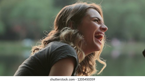 Girl speaking to friend in conversation, burts laughing out loud to friend joke. Real life authentic smile and spontaneous laugh - Shutterstock ID 1205450359