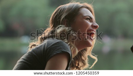 Girl speaking to friend in conversation, burts laughing out loud to friend joke. Real life authentic smile and spontaneous laugh