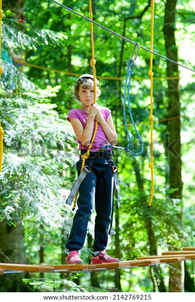The girl in special uniforms and sports\
uniforms trains in climbing in the rope\
Park.