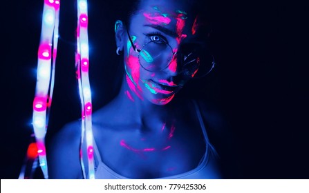 Girl spectacled, next to a garland. Talking eyes, neon light, paint