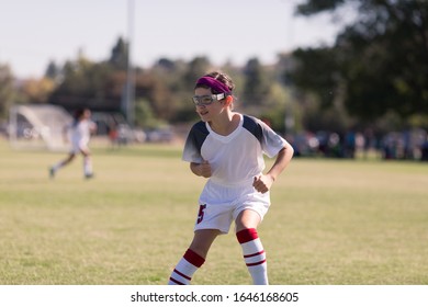 A Girl In Sports Goggles Is Playing Competitive Soccer.