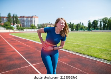 Girl in sportswear in stadium is exhausted and has pain during training and workout.Sports woman has a stomach ache. Outdoor sports and pain concept. - Powered by Shutterstock