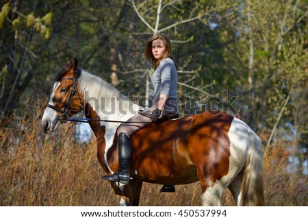 Girl sportswoman and her horse after a riding in the spring