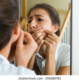 Girl squeezing pimple at home  - Shutterstock ID 296584781