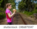 The girl in Sri Lanka enjoying fresh coconut water in hot summers on a railway track. In Sri Lanka, enjoying fresh coconut. 