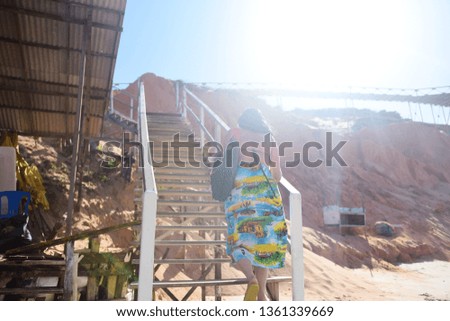 Girl in the stairs on the beach with bright sunflares.