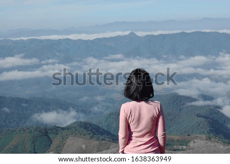 The girl standing alone on the top of the mountain, solitude and freedom concept.
