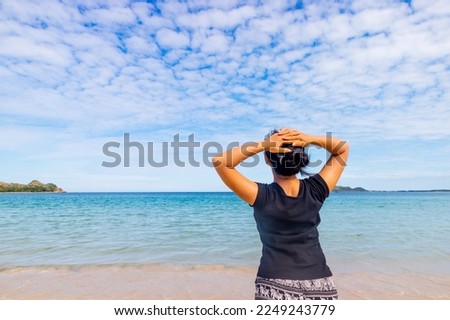 A girl is standing in front of a quiet beach.