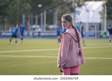 girl standing and looking at football players, blue football players uniform, football field, game, childhood, child, baby, kid - Powered by Shutterstock