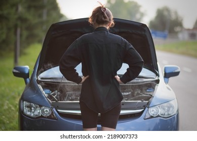 The Girl Is Standing Near The Open Hood Of The Car. The Car Needs Repair. With Smoke.