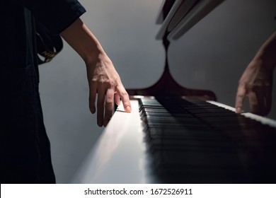 A Girl Standing Next To An Old Classic Piano Touching The Keys With Her Hand, A Girl Playing The Piano Close Up Blurred