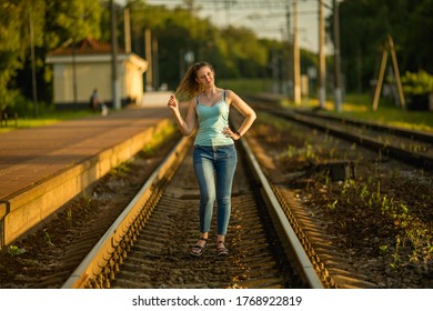girl standing on the railroad touching curly hair - Shutterstock ID 1768922819