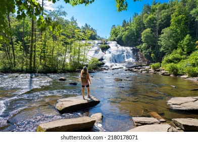 Girl Standing On The Rock Enjoying Beautiful Waterfall View. High Falls  Of Dupont State Forest In Brevard. Blue Ridge Mountains, Near Asheville, Western North Carolina, USA.