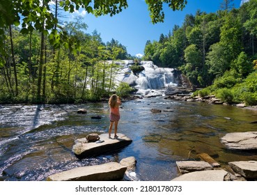 Girl Standing On The Rock Enjoying Beautiful Waterfall View. High Falls  Of Dupont State Forest In Brevard. Blue Ridge Mountains, Near Asheville, Western North Carolina, USA.