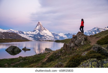 Girl standing on a rock / peak, admiring the Swiss Alps and Matterhorn peak in the background, Zermatt, Stellisee, Switserland 