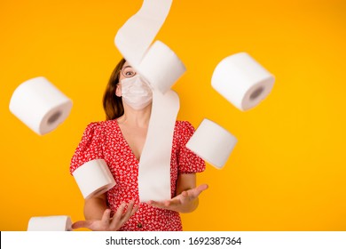 Girl Standing In A Red Summer Dress In A Protective Medical Mask. Throwing A Lot Of Toilet Paper In The Air On A Yellow Background