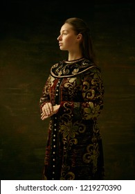 Girl standing in Russian traditional costume. Woman is wearing in old retro boyary outfit at darl studio