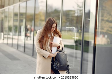 Girl standing in a spring city and hold documents in her hand