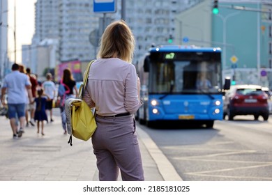 Girl standing at the stop and waiting to board the bus, public transport in summer city - Powered by Shutterstock