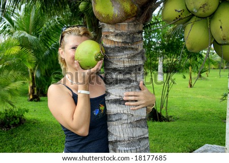 The girl standing under palm tree with coconut