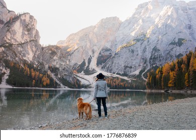 girl stands with a dog at the famous mountain lake Braies in Italy. Traveling with a pet. autumn mood - Powered by Shutterstock