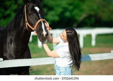 A girl stands next to a dark-brown horse