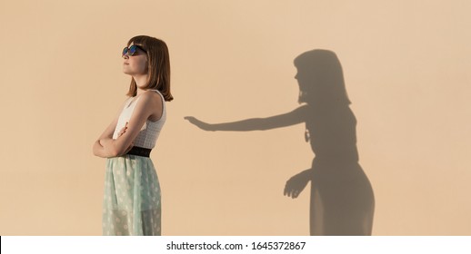 The Girl Stands In A Proud Pose. Her Shadow Is Trying To Make Contact With The Girl. Internal Conflict Of A Teenager. Emotional Concept.