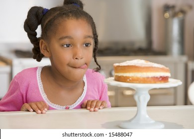 Girl Staring Longingly At Cake At Home Licking Lips