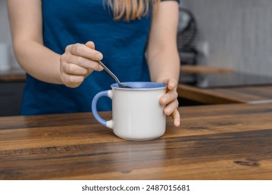 The girl stirs hot tea in a porcelain cup - Powered by Shutterstock