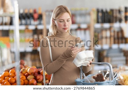 Girl in store scan QR code on yogurt label. In mobile app, buyer receive information about yogurt. They check manufacturer data in registry database of national agency
