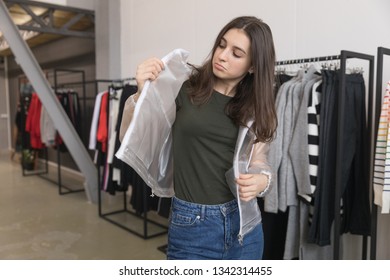 The girl in the store tries on a transparent jacket. - Shutterstock ID 1342314455