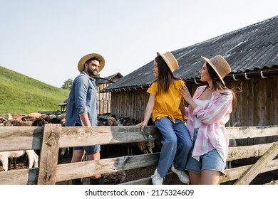 girl in straw hat sitting on wooden fence near mom and dad in corral
